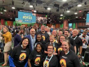 A group of people all wearing a 'Charlie's Sailblazer' t-shirt at the Dreamforce 2023 keynote.